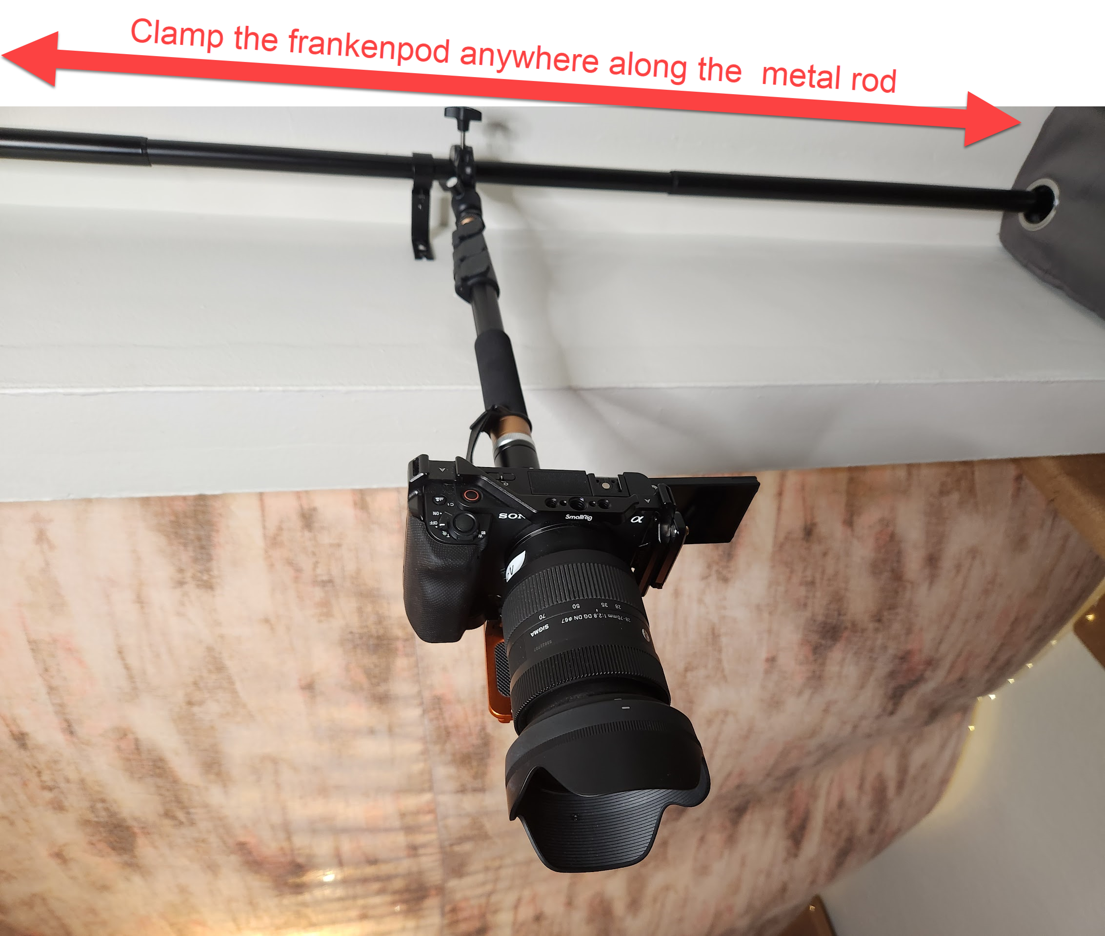 Camera hung from a metal curtain rod, photographing a tabletop